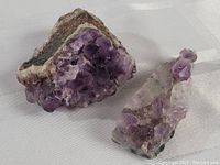 Photo showing two Canadian amethyst mineral specimens with visible purple crystals on natural rock bases.