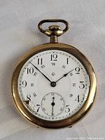 Front view of the antique Eaton pocket watch showing the dial, numerals and damaged crystal.