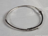 Sterling silver bracelet laid flat, showing overall shape and hinge.