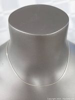 Front view of the thin sterling silver necklace on display, showing length and simplicity.