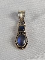 Front-facing close-up image of the vintage sterling silver pendant with blue stones showing polish and detail of twisted silver border.
