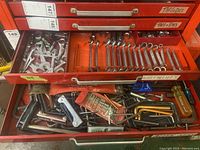 Two red metal drawers labeled with wrenches and containing tools