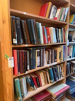 Five shelves filled with books of varying sizes and colors, packed mostly vertically with some horizontal stacks. Books cover history, classics, philosophy, and educational topics.