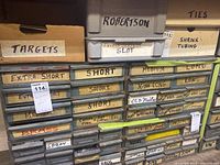 Photo of front of metal storage cabinet with multiple labeled drawers for assorted hardware and fasteners like nails, washers, screws, pins, brass, shrink tubing.