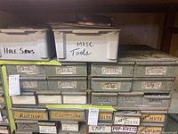 Overall view of metal cabinet with plastic bins labeled 'Hole Saws' and 'Misc. Tools' and multiple labeled drawers for hardware sizes and types