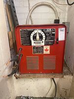 Front view of red welding unit showing control panel and cables