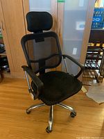 Front-left perspective showing overall chair frame, mesh back, seat cushion, armrests and headrest