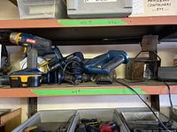 Shelf with Ryobi cordless drill, circular saw, reciprocating saw, and charger resting together showing lot contents