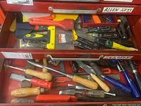 Drawer with a variety of scrapers, chisels, rasps, and wood files, showing different handle colors and brands with some dirt and wear.