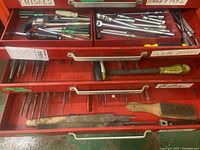 Top drawer with assorted socket wrenches, ratchets, extension bars, various screwdrivers, metal files including wood files, chisels, and a wire brush in a red toolbox.
