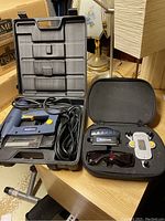 Electric stapler and laser level with cases on wooden table
