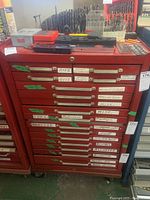 Front view of red 16-drawer tool chest with drawer labels and stainless steel handles.