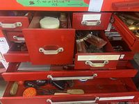 Full view of red metal drawers filled with hand tools, wrenches, screwdrivers, brushes, and pipes.