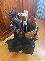 Photo showing bucket filled with hand tools including garden rake, claw hammer, screwdrivers, metal level, and soft tool bag.