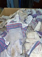 Close up of multiple fabric work gloves piled together showing wear and dirt.