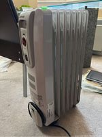 Side view showing the heater's 6 vertical fins, built-in power cord storage, and part of the control panel.