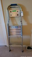 Front view of Reynolds aluminum folding step ladder with four steps, top platform, and padded handle.