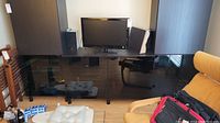 Full view of entertainment center showing lower console with TV on top and upper cabinets with open shelves on right side of photograph