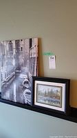 View including both prints: large black and white stretched canvas and smaller framed watercolor print.