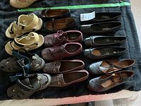 Photo showing 10 pairs of women's size 9.5-10 shoes and sandals including beige strappy sandals, brown loafers, maroon sneakers, black flats, and black T-strap Rockport shoes.