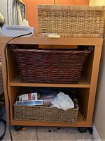 Bedside table with three wicker baskets shown with some contents in baskets.