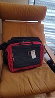 Two travel bags placed on a cushioned chair, front view showing zippered compartments and handles.