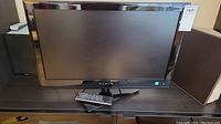 Front view of Fluid LED TV with remote placed on the stand, showing the screen and bezel.