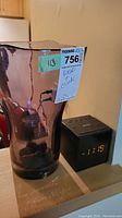 Purple art glass vase and Sony digital alarm clock with LED display showing 11:18