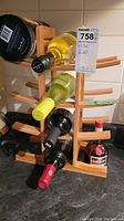 Front and side views of a light-colored wooden wine rack filled with various wine bottles and a small bottle next to it.