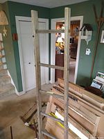Rustic wooden blanket ladder standing near wall, visible with multiple rungs and weathered wood texture.