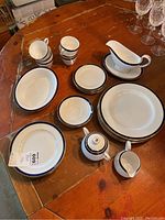 Photo showing the entire collection of Spode china including cups, saucers, plates, sugar bowl, creamer, and gravy boat on a wooden table.