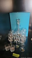 Full set showing Birks decanter with stopper, nine Bellfor aperitif glasses and two Itala shot glasses in front of light blue box