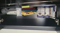 Open cabinet with scarves, packaged handkerchiefs, and unopened cologne bottle