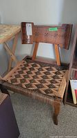 Front view of vintage wood framed chair with decorative curved back and woven seat