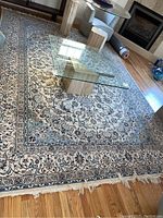 View of the wool oriental rug laid out on a hardwood floor, showing fringe, pattern and size.