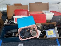 Overview of multiple trays and boxes containing mixed camera parts and accessories