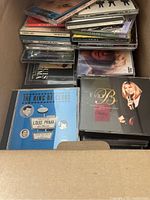 Box of assorted CDs showing titles like Louis Prima Greatest Hits and Barry Manilow.