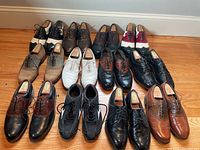 Full overhead shot showing all 15 pairs of men's dress shoes. Most have shoe forms inside. Shoes vary in colors from black, brown, tan, to white/red/black accents, including a pair of black sports shoes.