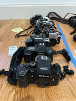 Front view of row of seven Nikon camera bodies lined on wood floor
