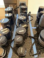 Overall view of eight cylindrical cases and loose lenses arranged on countertop.