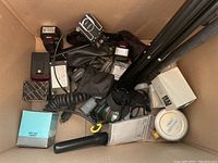 Box containing assorted flashes, cables, lens cap, filter cylinder