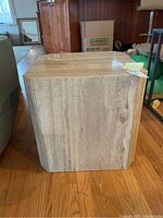 Front face and right side of travertine cube showing beige veining pattern.