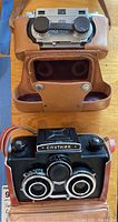 Both cameras in their leather cases on wooden surface