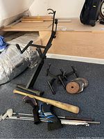 Wide view of the metal weight rack, weight plates, golf clubs, and wooden bat arranged on floor.