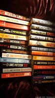 Shelf of assorted James Patterson novels showing 21 different titles in various colors and fonts on the spine