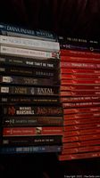 Books stacked showing titles and authors of thriller and romance novels.