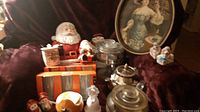 Photo shows the full assortment of items including the Pepsi tray at the back center, salt and pepper shakers at front, ceramic Santa figure, small jars and containers, and framed vintage print on the right.
