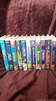 Photo showing 11 Disney VHS movies lined up, titles visible including Toy Story, The Lion King, Bambi, Aladdin, Cinderella, and others.