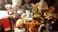 Photo shows assortment of various stuffed animals including a blond doll and two doll outfits (Santa suit and Christmas tree outfit). Animals include bear, elephant, rabbit, turtle, dog, monkey, tiger, lion, crab/lobster, and bird.