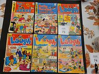 Photo showing six vintage Archie comics including Giant Archie Series Comics and Laugh series comics with colorful covers.